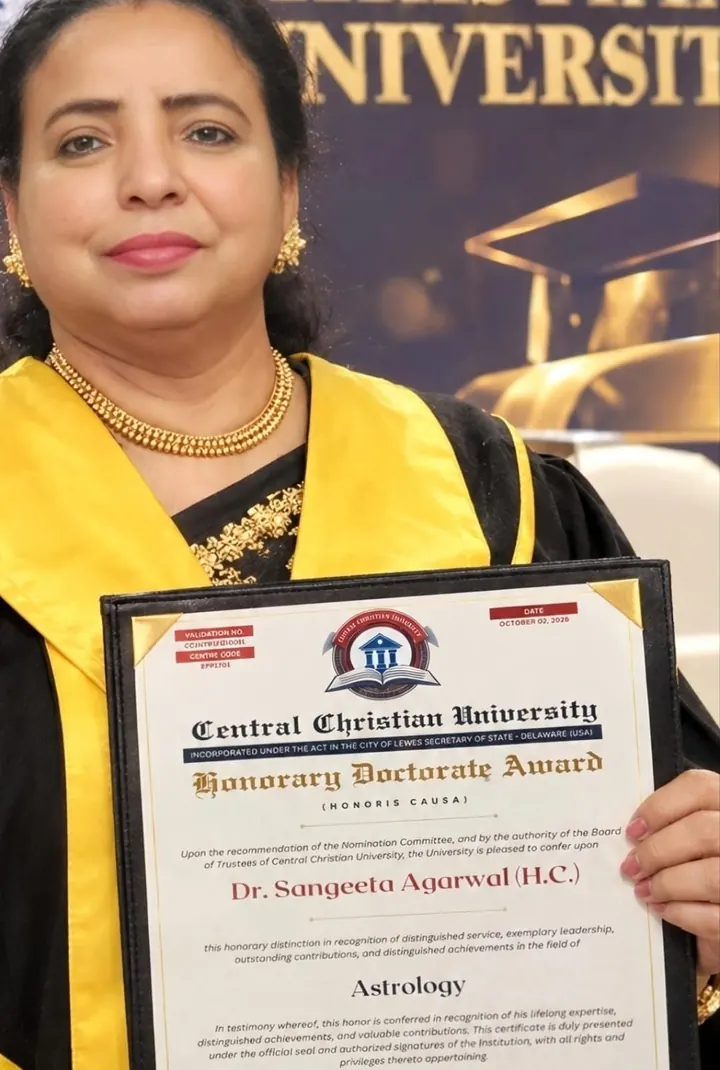 Sangeeta Agarwal in a graduation gown holding her Honorary Doctorate certificate